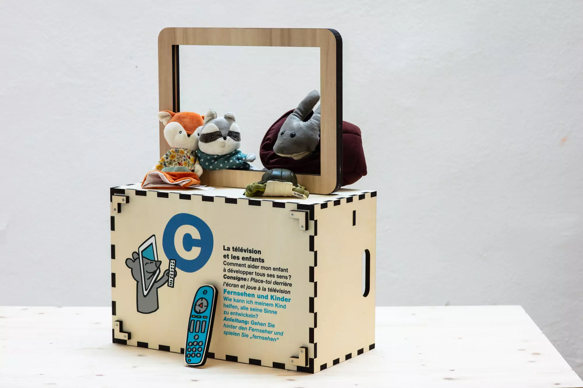 Caisse en bois transformé en télévision avec des marionnettes derrière le cadre