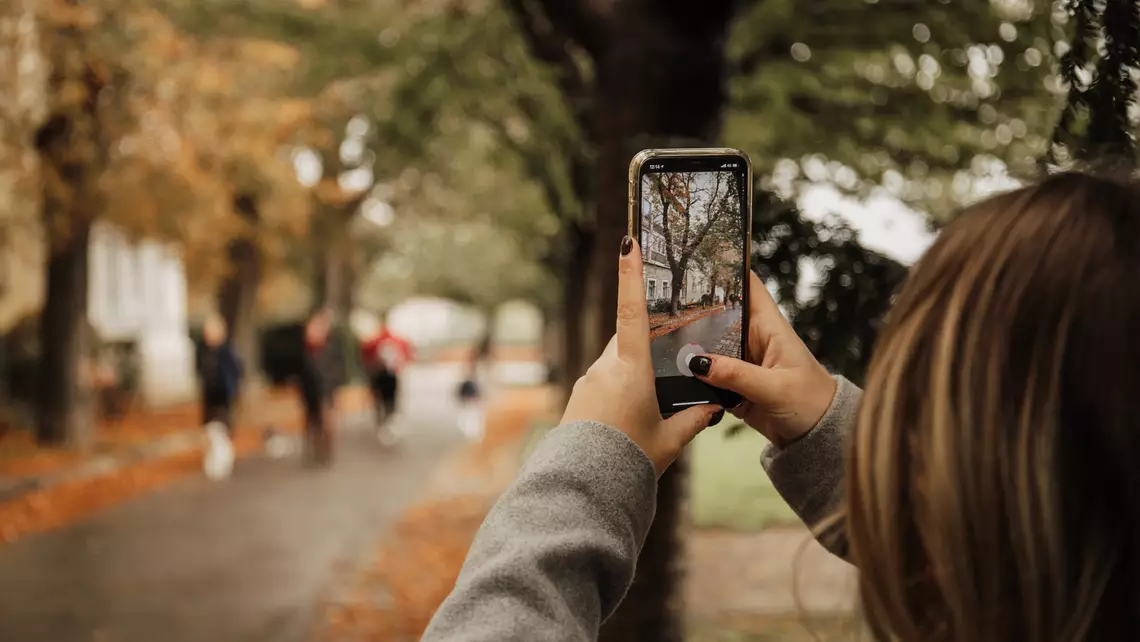 Une personne qui prend une photo dans une rue passante