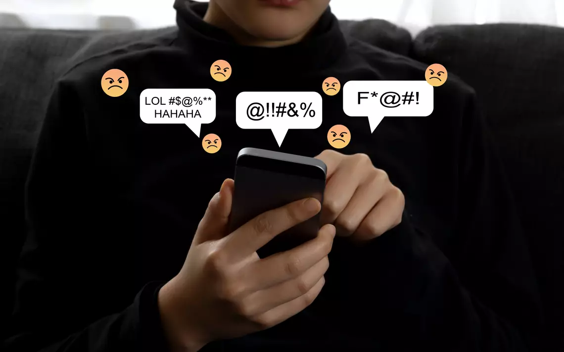 Un jeune tenant un smartphone d'où sortent des emojis négatives
